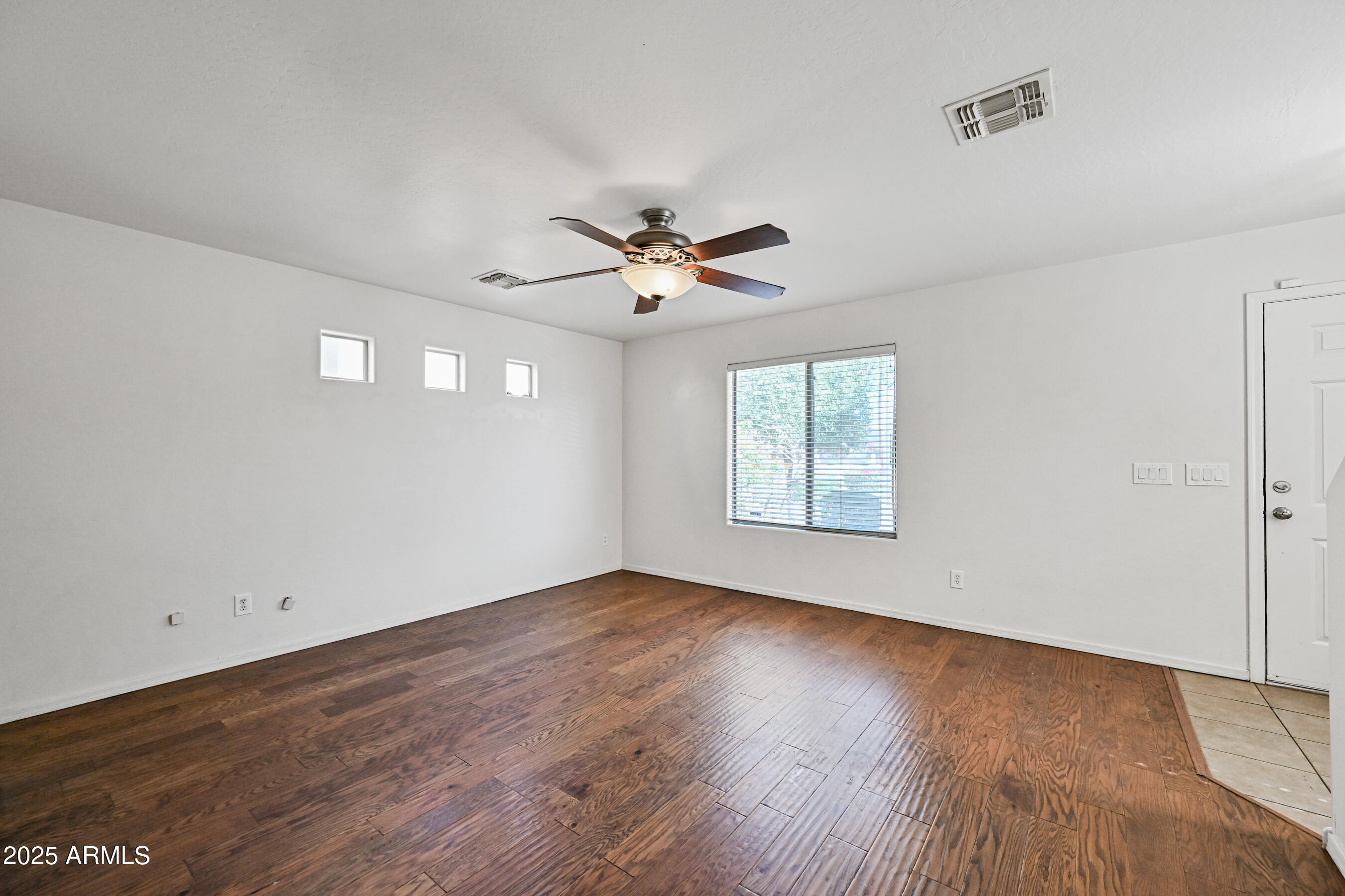 3726 West Pollack Street Phoenix, AZ 85041 - Photo 5 of 27 an empty room with wooden floor and ceiling fan