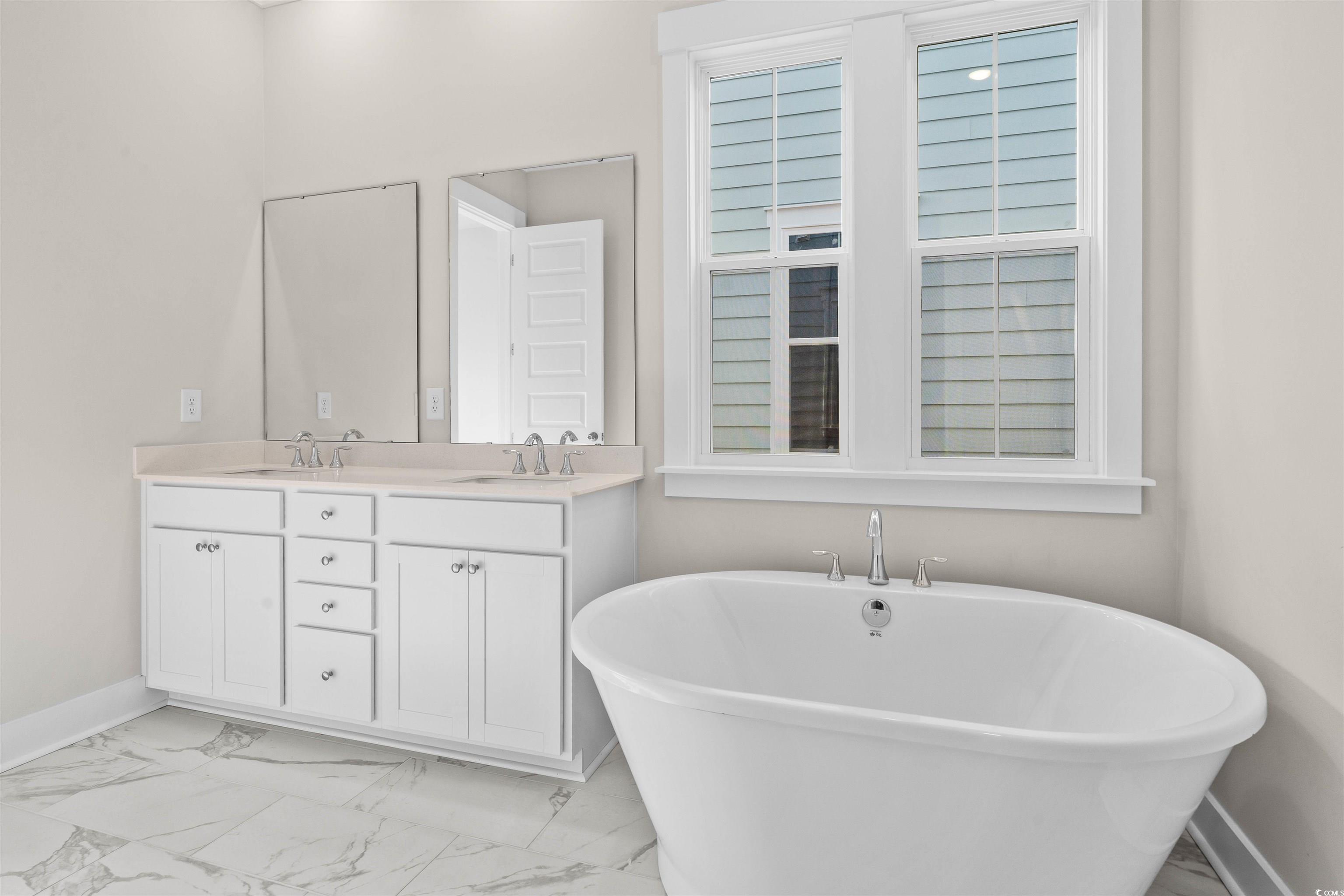 205 Atlantic Breeze Street Myrtle Beach, SC 29572 - Photo 16 of 28 Full bathroom featuring light marble finish floors, a freestanding tub, and double vanity