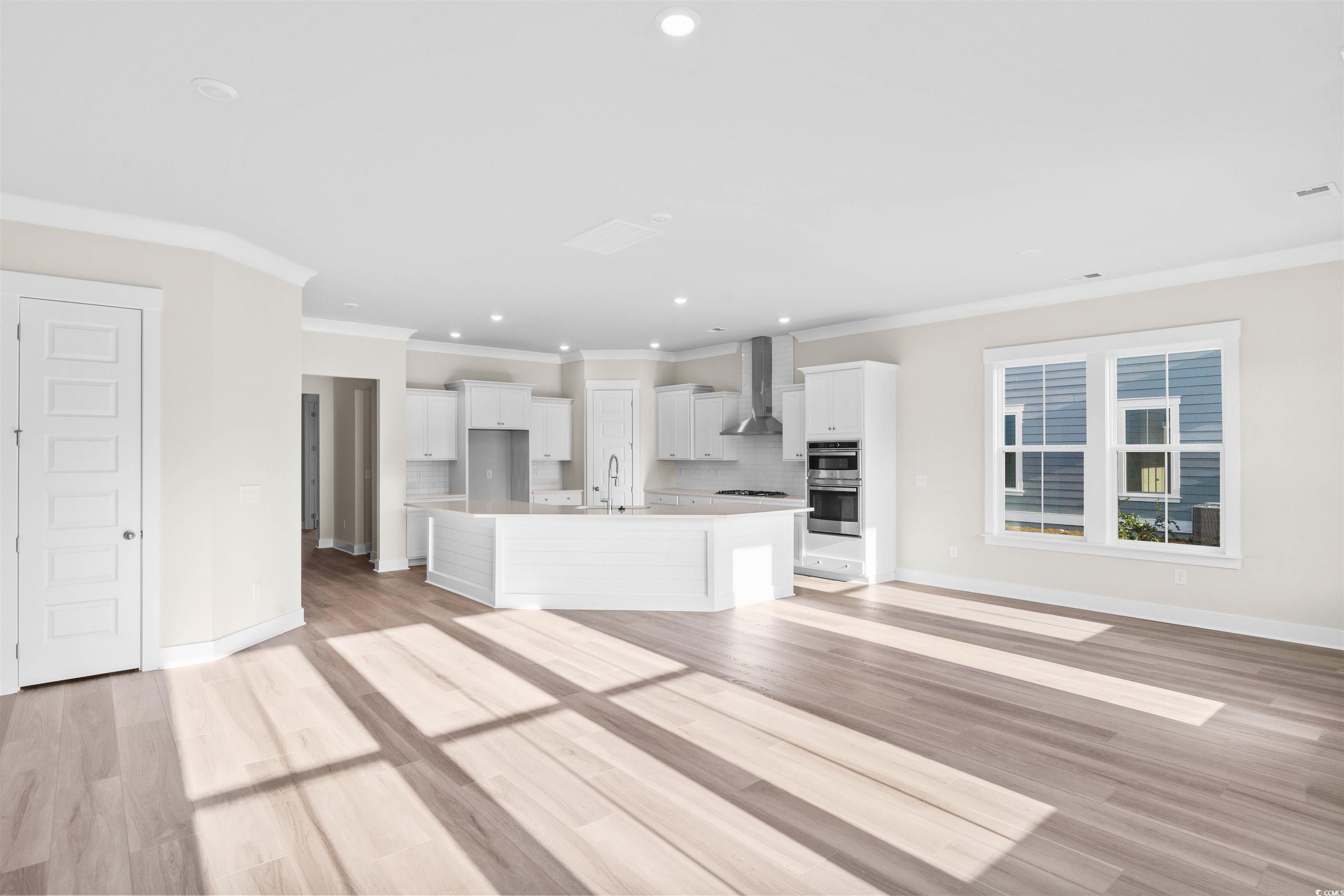 205 Atlantic Breeze Street Myrtle Beach, SC 29572 - Photo 28 of 28 Kitchen with crown molding, an island with sink, recessed lighting, light wood-type flooring, and open floor plan