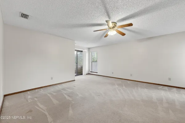 an empty room with windows and fan