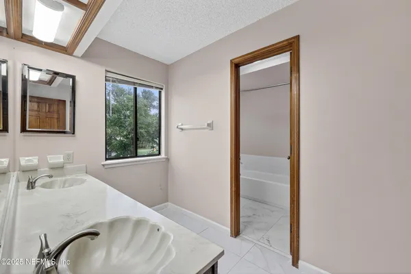 a bathroom with a tub sink and mirror