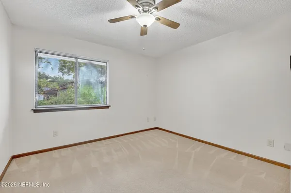 an empty room with a window and a fan