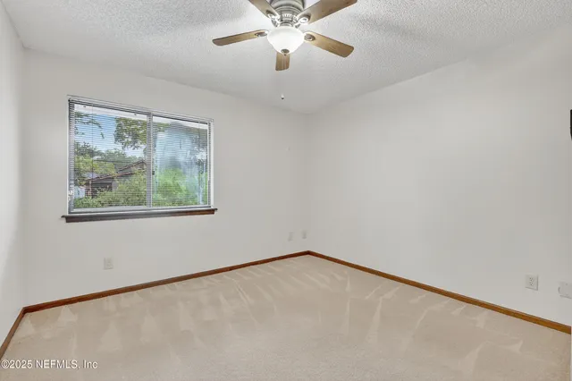 an empty room with a window and a fan