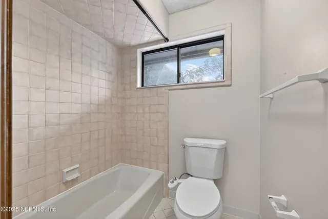 a white toilet sitting next to a bath tub and a shower