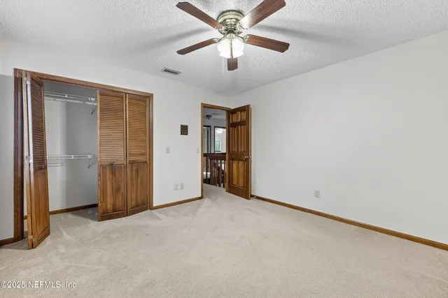 an empty room with closet and a chandelier fan