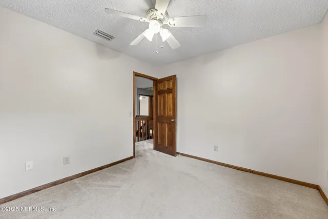 an empty room with a chandelier fan and windows