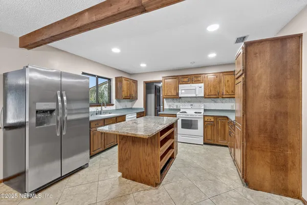 a kitchen with stainless steel appliances granite countertop a stove top oven a refrigerator a sink and dishwasher