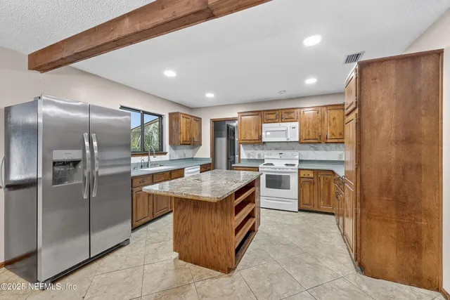 a kitchen with stainless steel appliances granite countertop a stove top oven a refrigerator a sink and dishwasher