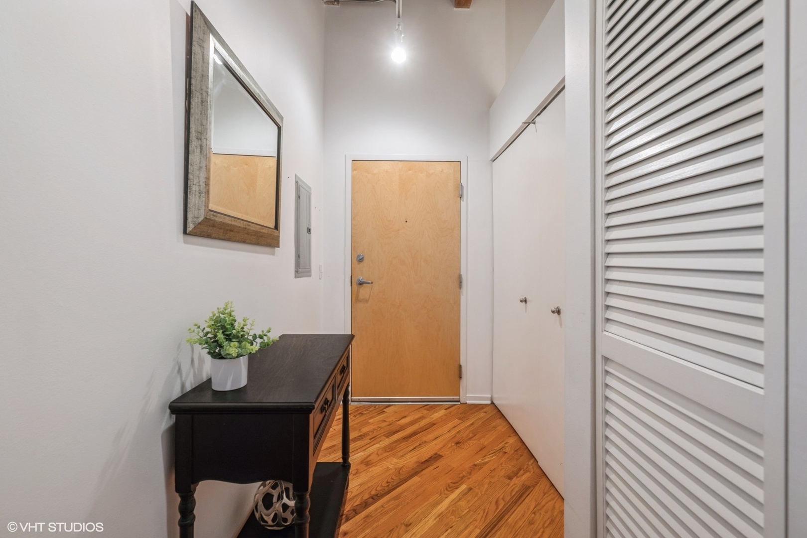 1040 West Adams Street, Unit 442 Chicago, IL 60607 - Photo 22 of 23 a view of a hallway to a house with wooden floor and a potted plant