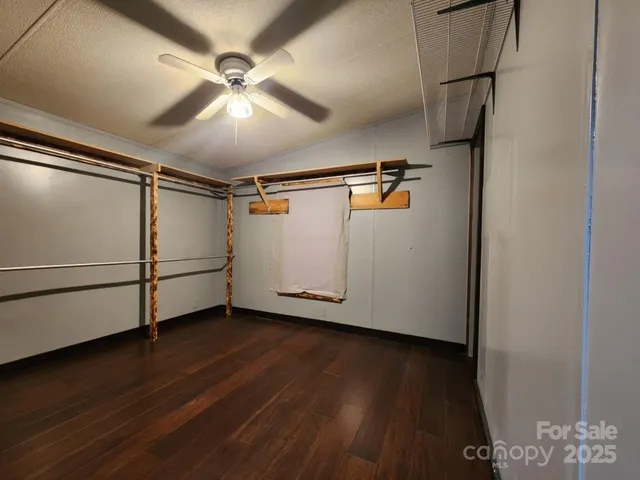a view of an empty room with wooden floor and a ceiling fan