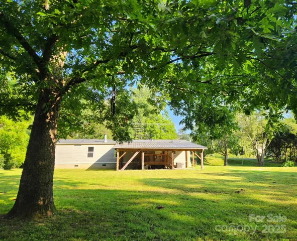 a view of a big house with a big yard and large trees