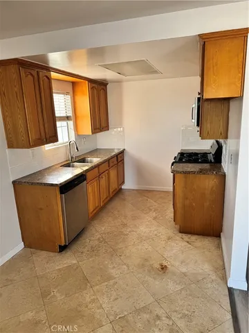 a kitchen with granite countertop a sink a stove top oven a granite counter space and a window