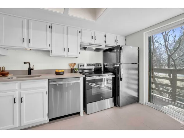 a kitchen with white cabinets a sink dishwasher and a stove with wooden cabinets