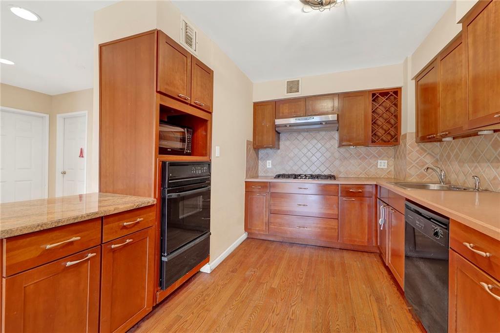 52 92nd Street, Unit 7C Brooklyn, NY 11209 - Photo 6 of 22 a kitchen with granite countertop stainless steel appliances and wooden cabinets