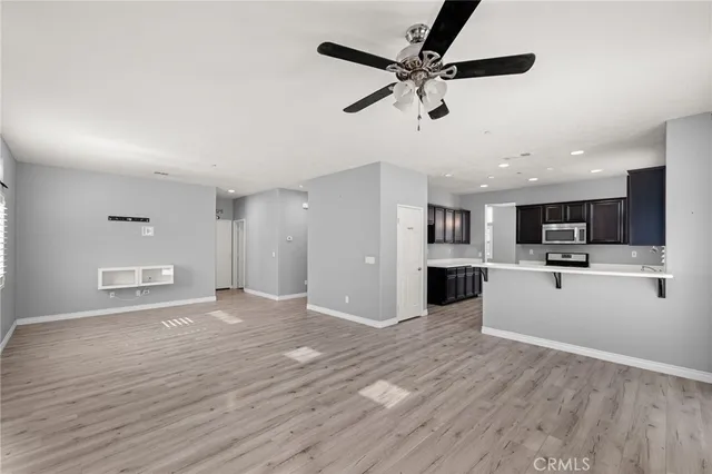a view of a big room with wooden floor and a kitchen
