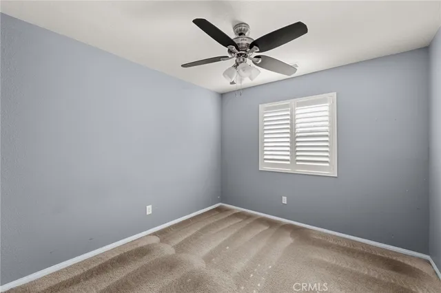 an empty room with a window and a fan