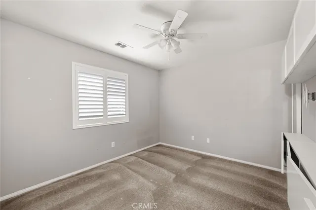 an empty room with a window and a fan
