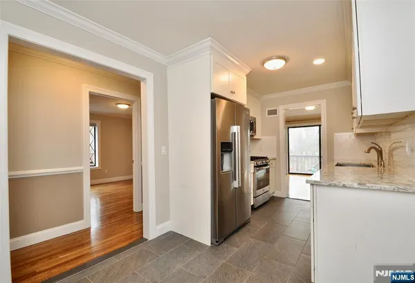 a bathroom with a granite countertop sink mirror and refrigerator