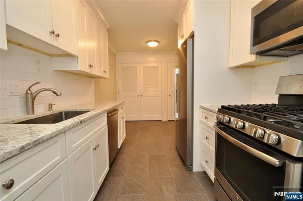 a kitchen with granite countertop a sink stove and refrigerator