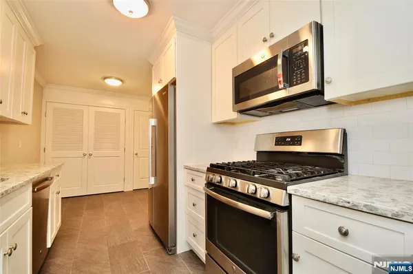 a kitchen with stainless steel appliances granite countertop a stove a microwave and a refrigerator