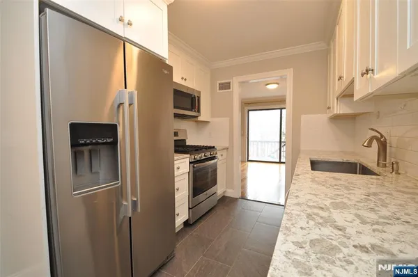 a kitchen with stainless steel appliances granite countertop a refrigerator a stove and a sink with wooden floor
