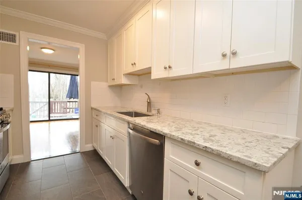 a kitchen with granite countertop white cabinets and a sink