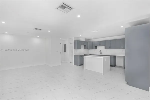 a large white kitchen with kitchen island a sink white cabinets and stainless steel appliances