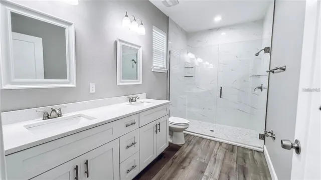 a bathroom with a double vanity sink toilet mirror and shower