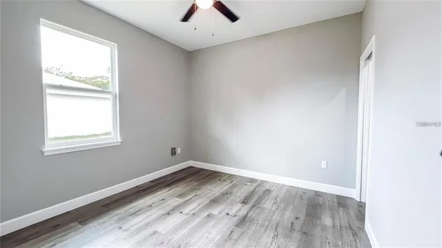 an empty room with a window and a ceiling fan