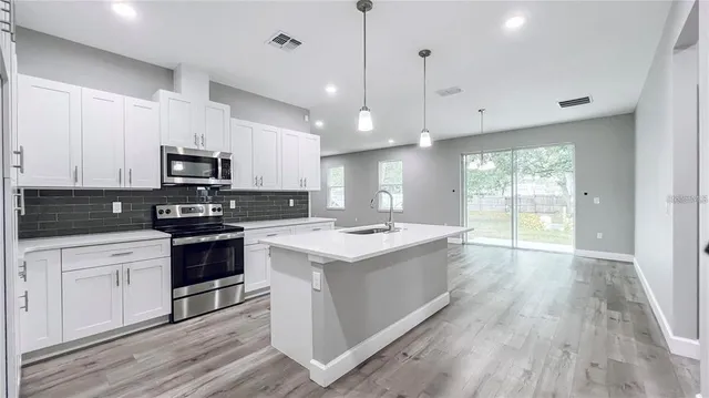 a kitchen with kitchen island granite countertop a stove a sink and a microwave