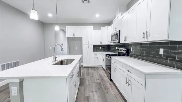 a kitchen with stainless steel appliances granite countertop a sink a stove and a refrigerator