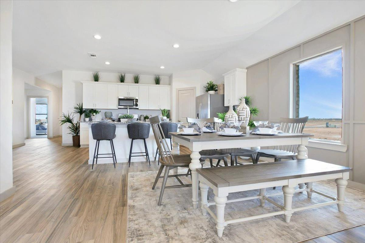 a view of kitchen with stainless steel appliances granite countertop dining table chairs and sink