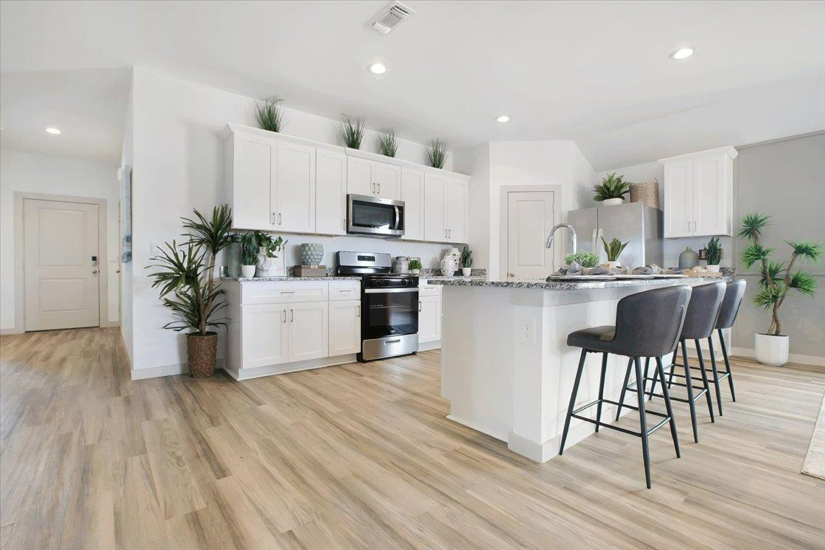 7415 8th Street Lubbock, TX 79416 - Photo 11 of 22 a kitchen with stainless steel appliances a dining table chairs microwave and cabinets