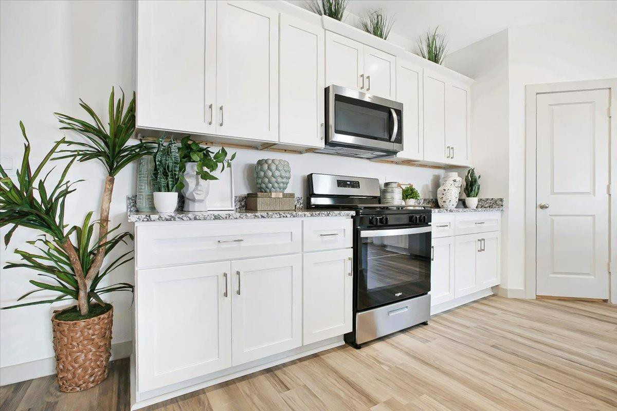 7415 8th Street Lubbock, TX 79416 - Photo 9 of 22 a kitchen with white cabinets stainless steel appliances and a potted plant