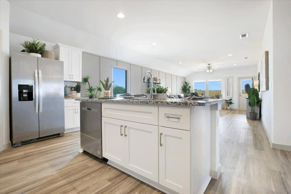 7415 8th Street Lubbock, TX 79416 - Photo 10 of 22 a kitchen with stainless steel appliances kitchen island granite countertop a refrigerator sink and cabinets