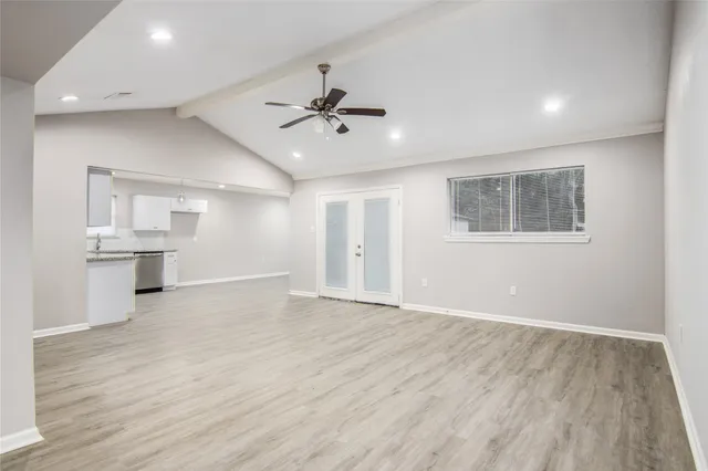 a view of an empty room with a kitchen and a window