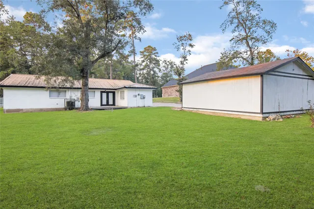 a view of house with a big yard and large trees