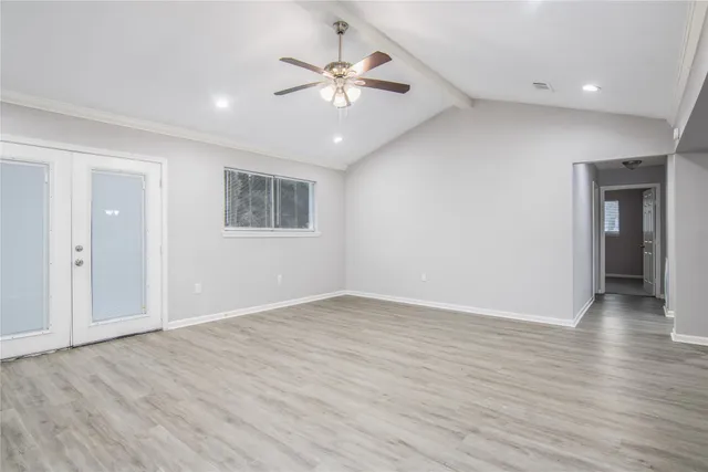 an empty room with wooden floor and ceiling fan