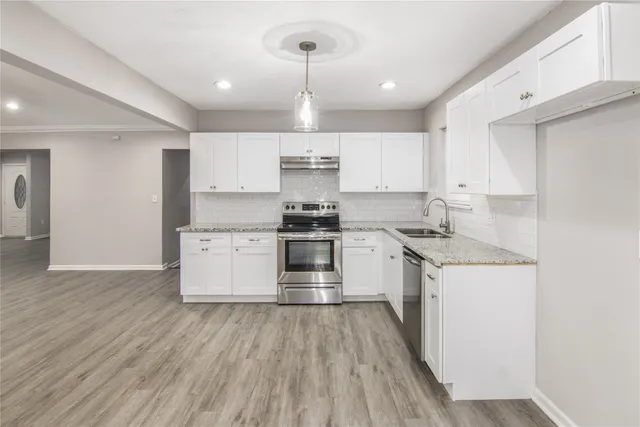 a kitchen with granite countertop a stove a sink and a refrigerator