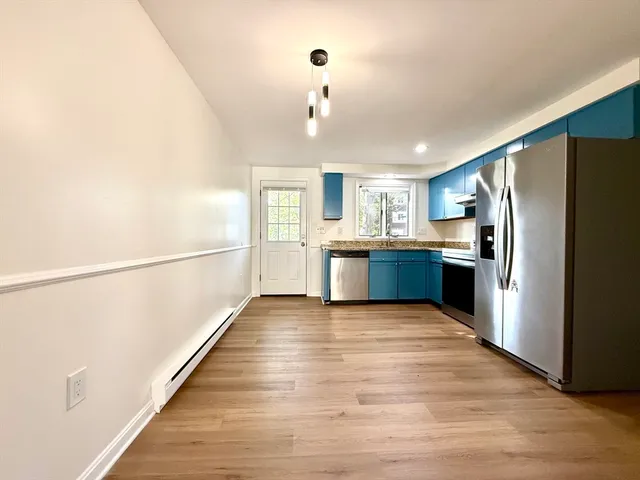 a large kitchen with wooden floor and stainless steel appliances