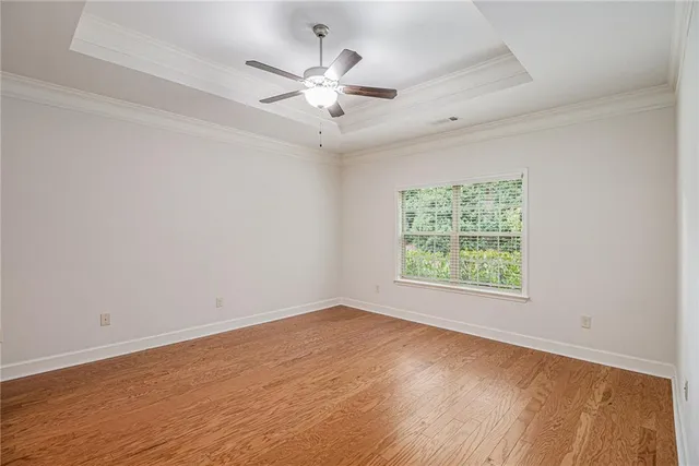 an empty room with wooden floor chandelier fan and window