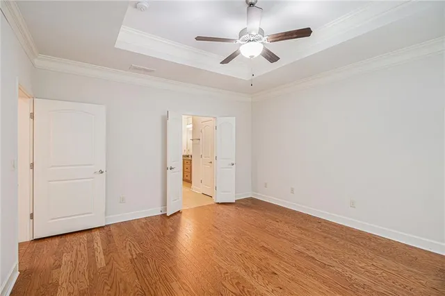 an empty room with wooden floor and ceiling fan