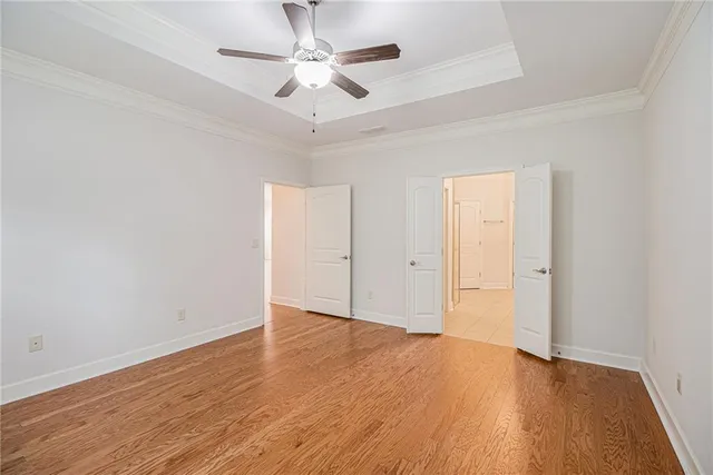 an empty room with wooden floor and ceiling fan