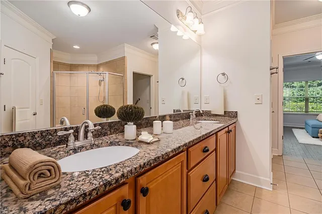 a bathroom with a granite countertop double vanity sink a mirror and a shower