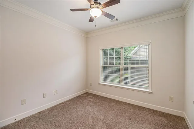 an empty room with chandelier fan and windows