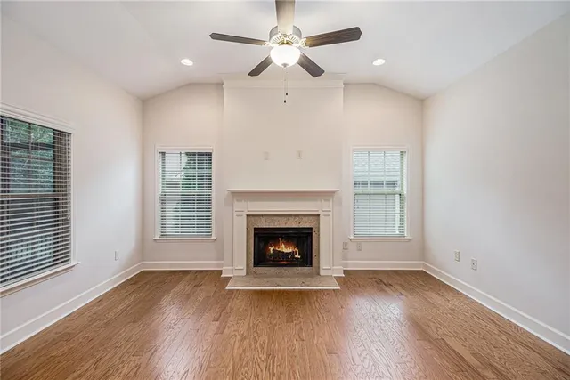 an empty room with wooden floor fireplace cabinet and windows
