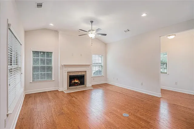 an empty room with wooden floor fireplace cabinet and windows