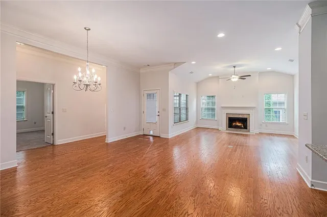 a view of an empty room with wooden floor fireplace and a window