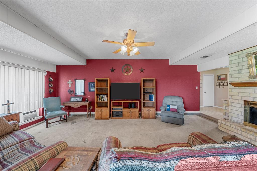 116 Boleman Drive Hewitt, TX 76643 - Photo 7 of 38 Living area featuring a textured ceiling, a fireplace, a ceiling fan, and carpet flooring