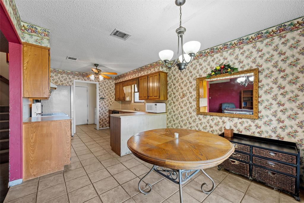 116 Boleman Drive Hewitt, TX 76643 - Photo 10 of 38 Dining space featuring a textured ceiling, light tile patterned floors, wallpapered walls, a ceiling fan, and a chandelier